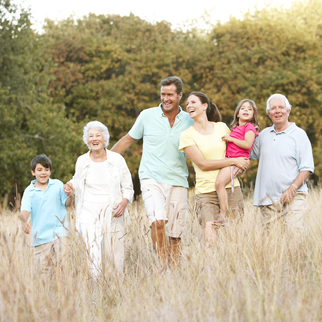 Three generations of a family walking happily through a field, symbolising the importance of family trust for safeguarding assets and securing the future